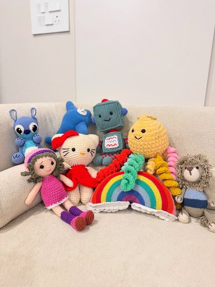 A whole family of our amigurumi toys together. You can see the variety we offer, from Stitch and Hello Kitty to a rainbow plush and a friendly lion.