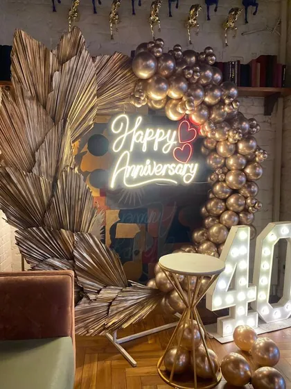 This shot focuses on the elegant details of the 40th-anniversary setup, including the custom neon sign with heart accents and the stylish cake table, perfect for capturing special moments.