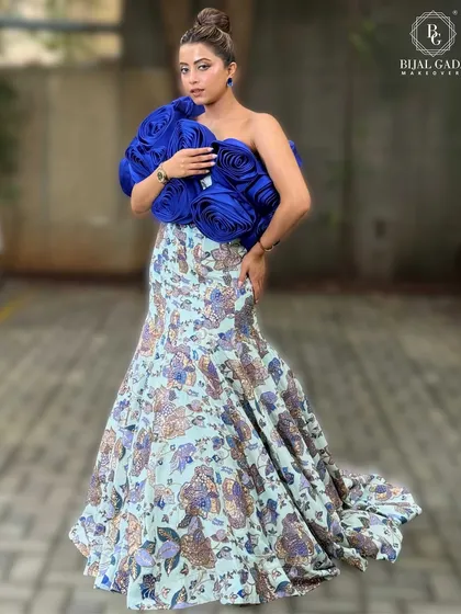 A full-body pose showcasing the entire ensemble. The makeup is designed to complement the unique silhouette and colors of the dress.
