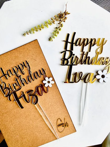 A side-by-side comparison of two custom birthday toppers, "Happy Birthday Fiza" and "Happy Birthday Iva," both featuring delicate floral accents.