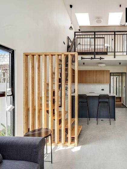 This 550 sq. ft. prefab home features a loft-style design with a mezzanine bedroom, maximizing vertical space. The open-plan living area includes a kitchen, dining space, and living room, all under a high ceiling with skylights.