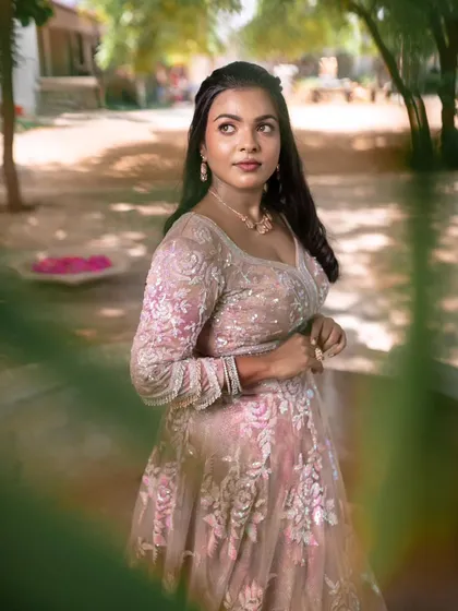 A model posing amidst greenery, showcasing a subtle and elegant reception look.