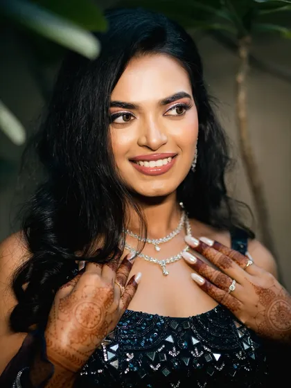 A stunning close-up of the bride, showcasing her flawless makeup and intricate diamond necklace. Her happy, confident smile makes this a radiant and beautiful portrait.