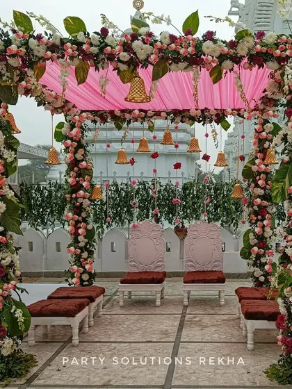 I designed this elegant wedding mandap for a ceremony held at a temple, blending seamlessly with the sacred architecture. The structure is adorned with pillars of fresh flowers and foliage, a soft pink canopy, and hanging temple bells to bless the couple's union.