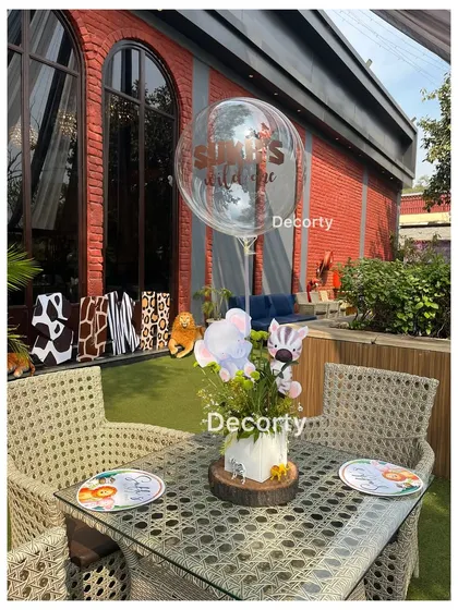 An outdoor table setting for a jungle party, with a custom balloon and themed centerpiece.