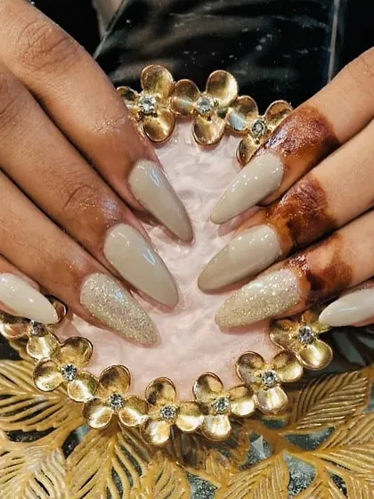 A sophisticated set of long, stiletto nails in a solid greige color with a single glitter accent nail.