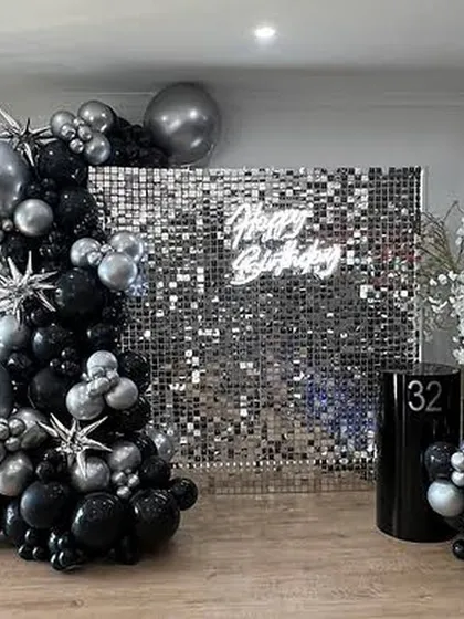 This black and silver theme is the definition of glam. A silver sequin wall, a neon sign, and a dramatic balloon arch with starburst accents create a high-end, celebratory look.