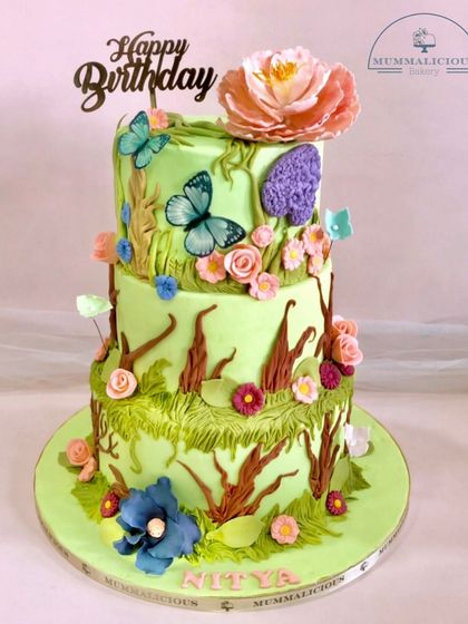 An enchanted garden brought to life. This three-tiered cake is a wonderland of sugar flowers, branches, and butterflies, creating a whimsical and breathtaking piece of edible art for a special birthday.