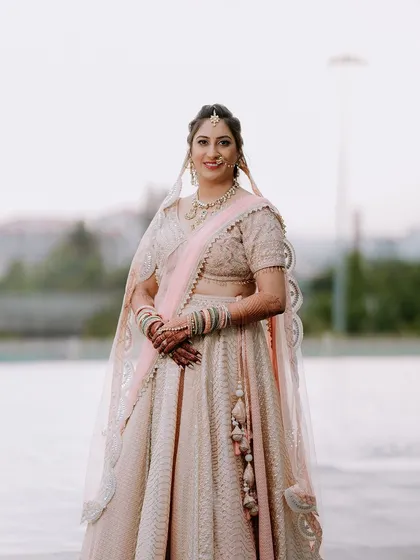 A full-length portrait of a bride in her elegant pastel lehenga, captured outdoors.