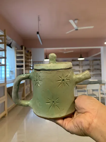 A lovely hand-built teapot with star carvings, created by a young student.