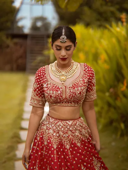 This is a modern take on a classic bridal look. The rich red lehenga is complemented by a bold red lip and defined eyes, creating a regal and timeless aesthetic for any bride's special day.