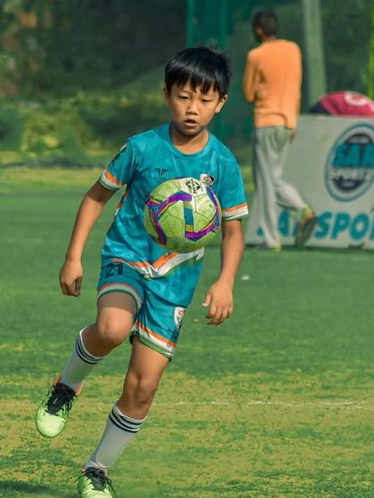A young player controls the ball with his chest, an advanced skill for his age.