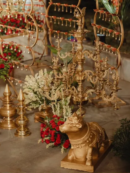 A collection of traditional brass decor, including a Nandi statue and ornate multi-tiered lamps (deepams). These elements were placed around the mandap to enhance the authentic, regal, and spiritual feel of the ceremony.
