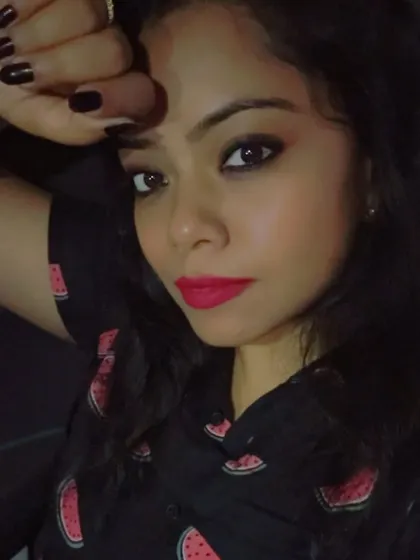 A close-up selfie showing a bright pink lip and dark nails, contrasting beautifully with the watermelon-print dress.
