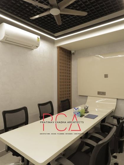 A smaller, functional meeting room with a clean design, gridded ceiling, and a large whiteboard for brainstorming sessions.