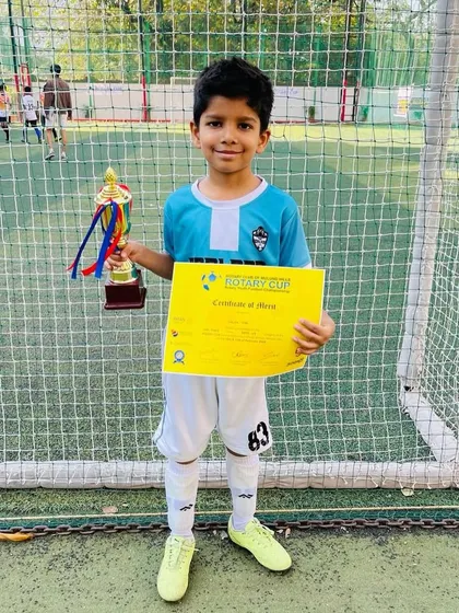 An Under-7 player proudly holds his trophy and certificate after winning a bronze medal in his very first tournament.