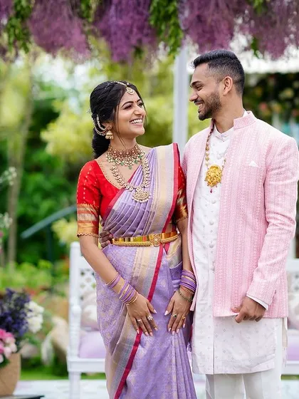 It's all about the happy couple. Shreya and Siddhanth sharing a smile under a canopy of hanging wisteria, surrounded by the soft lilac and lavender decor of their engagement ceremony. This is what joy looks like.