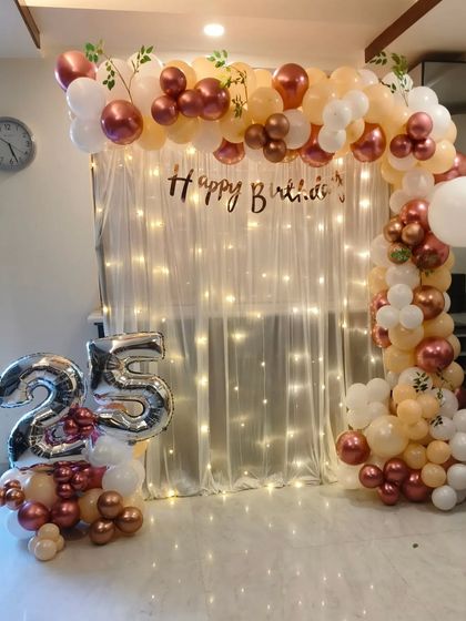 The same elegant 25th birthday setup, showing the full balloon arch against the fairy light curtain.