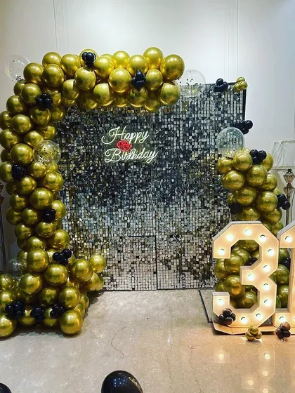 A bold and glamorous 31st birthday setup. The decor features a full arch of gold chrome balloons against a silver shimmer wall, complete with a neon sign and marquee numbers.