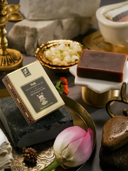 A close-up composition for Zeva's 'Nak' bath soap. We used contrasting textures of smooth stone, delicate lotus petals, and ornate brass to create a visually interesting and culturally rich setting for the product.