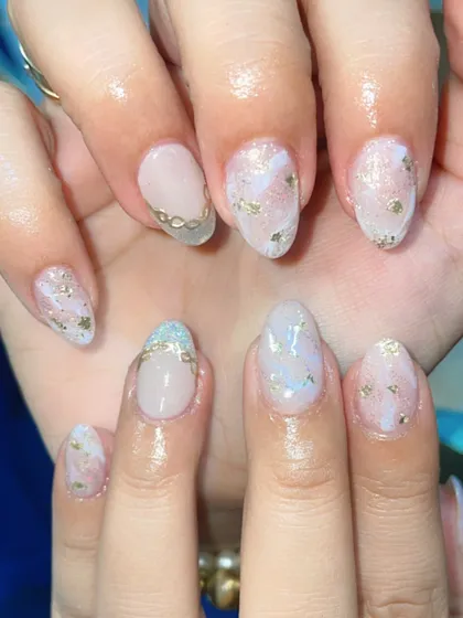A dreamy, ethereal look. These nails feature a milky white base with delicate gold foil flakes and a subtle gold chain accent for a touch of sophisticated charm.