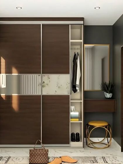 A bedroom wardrobe with sliding doors in a dark wood finish. The design includes a mirrored panel and an attached vanity table, creating a functional and space-saving dressing area.