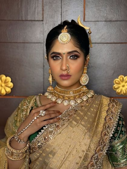 A close-up of a model in a traditional gold-look saree, adorned with heavy temple jewellery, including a statement choker and hathphool.