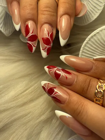 Another angle of our stunning red floral French manicure. The sharp almond shape of the nails provides the perfect canvas for this detailed and artistic hand-painted design.