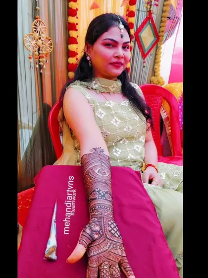A client looking elegant at a wedding function with her full-arm mehandi. The design complements her outfit beautifully.