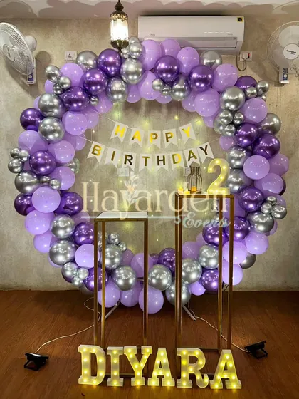 A large balloon ring in purple and silver, with pedestals and marquee letters, creating a grand setup for a 2nd birthday.
