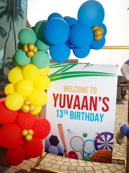 A personalized welcome sign for Yuvaan's 13th birthday sports party, decorated with a colorful balloon arrangement.