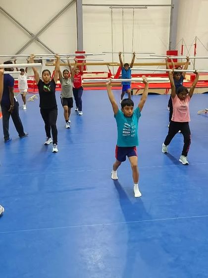 A group of young gymnasts practicing overhead lunges. These foundational exercises build stability, coordination, and strength, which are crucial for long-term athletic development.