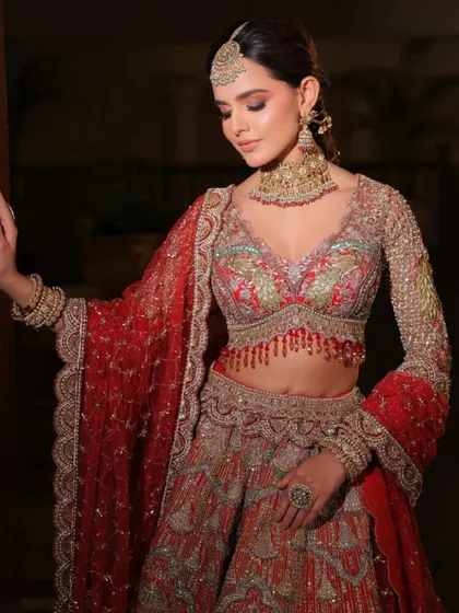 A three-quarter view of the stunning red bridal lehenga. The way the dupatta is draped showcases the detailed embroidery on the sleeves and border.
