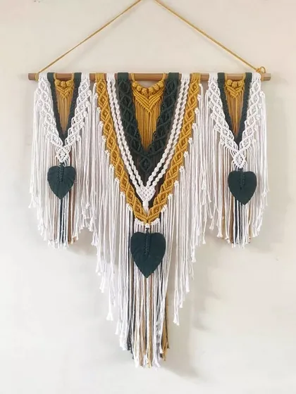 A clean shot of our popular three-panel macrame wall hanging. The design features a striking combination of mustard yellow, deep green, and off-white cotton.