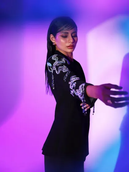 From a spring summer lookbook, this shot captures a blazer with abstract sequin embroidery. The cool-toned, dual-color lighting enhances the futuristic and edgy feel of the design.