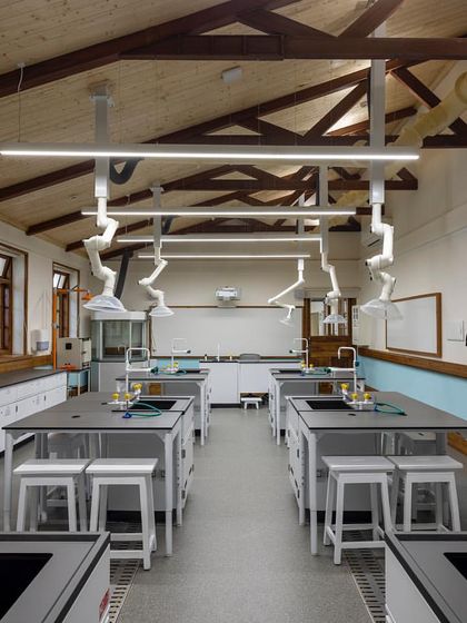 The fully retrofitted chemistry lab, showing the exposed heritage trusses and wooden ceiling alongside state-of-the-art ventilation hoods and flexible workstations.