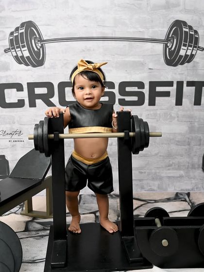 This future fitness enthusiast is ready to lift. The custom-made props and detailed backdrop make this gym-themed shoot a standout choice for a creative baby portrait.