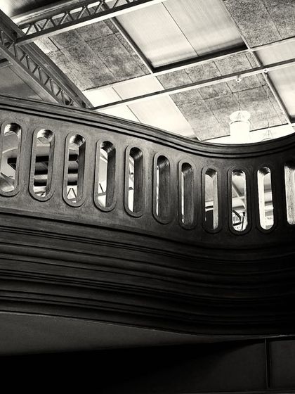 A perspective that showcases the undulating form of the mezzanine railing against the industrial ceiling structure.