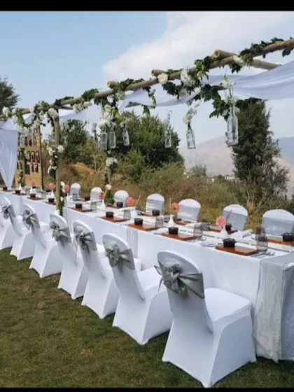 An elegant outdoor dining setup for a destination wedding. The long table is decorated with a simple white runner and floral arrangements, allowing the mountain view to be the main attraction.