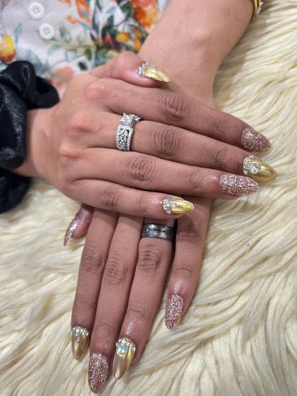 A full view of this ultra-glamorous nail set. The combination of gold chrome, rose gold glitter, and large rhinestone clusters creates a look of pure luxury.