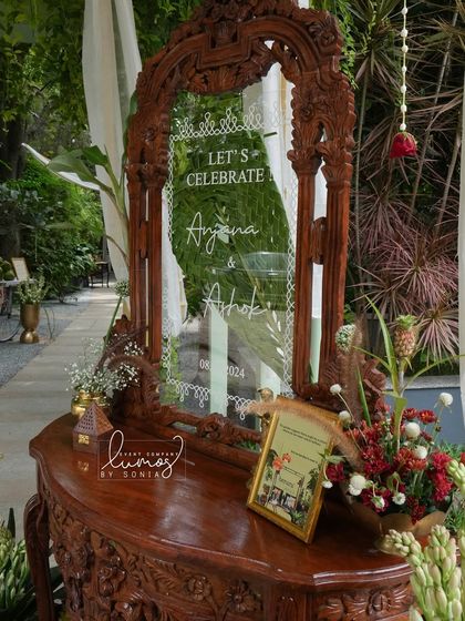 A detailed shot of the welcome mirror, framed by a carved wooden structure and adorned with fresh flowers, setting a celebratory tone.