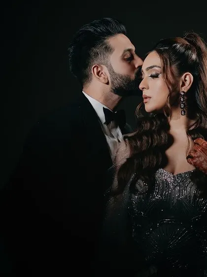 A tender moment between the couple. The groom's gentle kiss on her forehead is a classic expression of love and protection, captured with soft, dramatic lighting to enhance the intimacy.