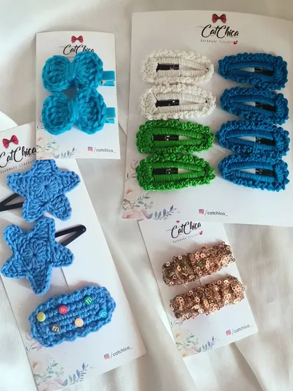 An assortment of our crochet clips, including blue bows, blue stars, and colorful barrettes. You can mix and match to create your own unique style.