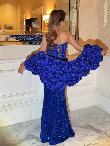 The back of the royal blue gown, showing its unique structure and the model's sleek ponytail.