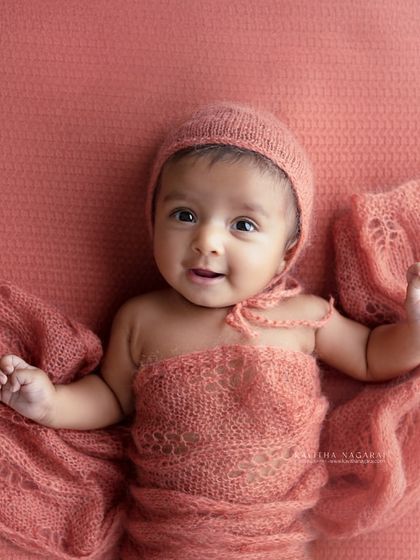 An older newborn waves hello, full of smiles and personality. This photo is a great example of the beautiful, interactive portraits we can create after the first few weeks.