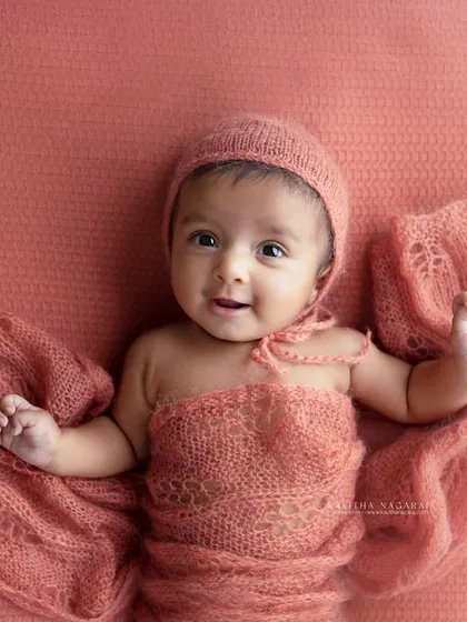 An older newborn waves hello, full of smiles and personality. This photo is a great example of the beautiful, interactive portraits we can create after the first few weeks.