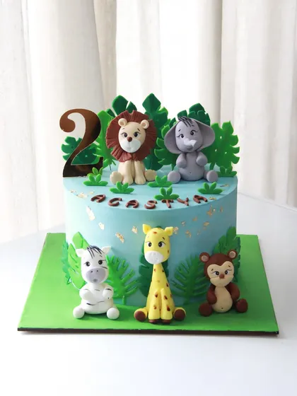 A wild jungle adventure for a 2nd birthday! This cake features a whole crew of cute, handmade fondant animals like a lion, elephant, giraffe, zebra, and monkey.