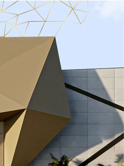 A close-up showing the tension and resolution between interlocking dark tiles and a smooth cylindrical form. Vertical slots admit light, softening the mass and moderating the scale of the industrial structure.