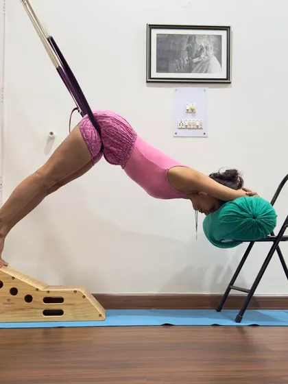 This supported Adho Mukha Svanasana uses a rope sling and a small bench. The rope provides traction for the lumbar spine, while the bench supports the head and chest. This variation is highly therapeutic for back pain, as it creates space and decreases compression on the nerves.