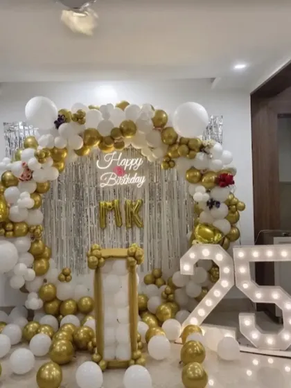 This elegant white and gold balloon backdrop is customized for a 25th anniversary celebration. The large light-up "25" marquee numbers serve as a brilliant photo prop and a central element of the decor.